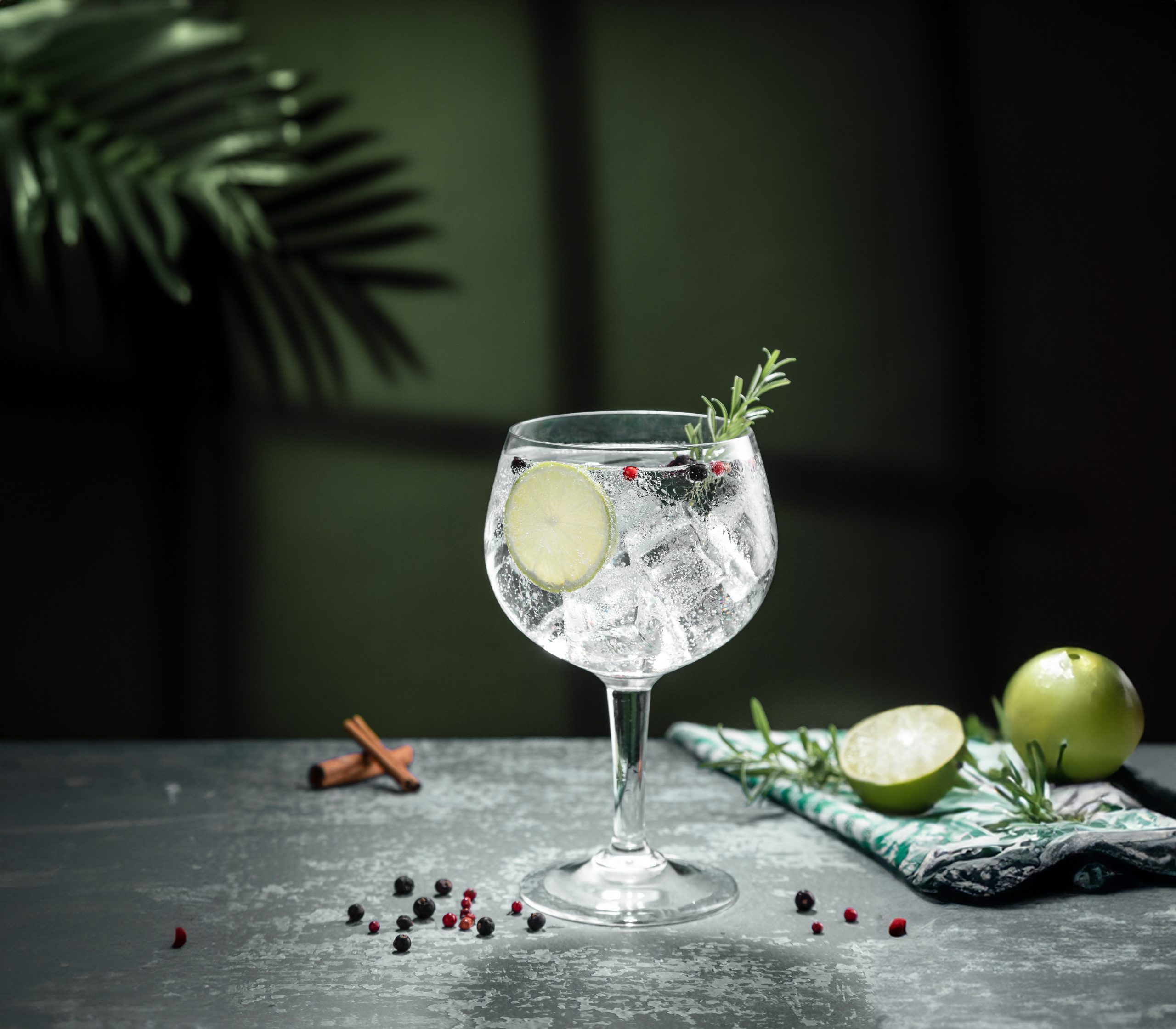 gin tonic cocktail and shadows next to the window on dark concr